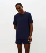 Conjunto de pijama masculino compuesto por una remera de cuello redondo y mangas cortas, y una bermuda con cintura elástica. Presenta un diseño liso en color azul marino con textura acanalada.