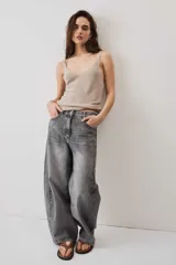 Jeans de corte barrel en tono gris deslavado, con diseño amplio y tachas decorativas a lo largo de las costuras laterales y los bolsillos delanteros.