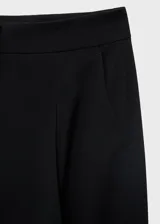 Pantalón wide leg de tiro medio color negro, con diseño largo, bolsillos laterales, bolsillos de ribete posteriores y detalle de pinzas. Cuenta con cierre oculto de botón, gancho y cremallera, e incluye forro interior.