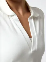 Remera polo de piqué color blanco, con manga corta abullonada, escote en V profundo y cuello clásico.