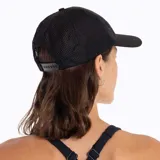 Gorra tipo trucker de color negro con paneles laterales y traseros de malla. Presenta un parche circular bordado en el panel frontal con el logo de Merrell y un diseño de montañas.