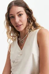 Chaleco corto color marrón topo, con escote en V asimétrico y cierre cruzado con botones.