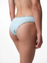 Bombacha tipo bikini de tiro medio confeccionada en algodón acanalado blanco, con bordes terminados en ribete con estampado animal print.