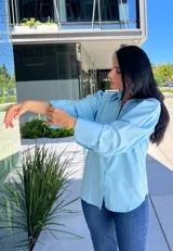 Camisa celeste de manga larga con puños anchos, cuello clásico y cierre frontal abotonado.