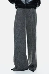Pantalón de punto con tiro alto y cintura elástica oculta. Presenta un corte de pierna recta con pliegues frontales y un estampado de espiga en tonos grises.
