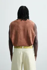 Camiseta tank (sin mangas) de corte relajado, color terracota con efecto lavado y estampado frontal de estrellas en blanco. Presenta cuello redondo y acabados deshilachados en las sisas y el ruedo.