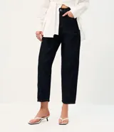 Pantalón de jean con corte new carrot, de cintura alta y estructura firme. Presenta un diseño holgado en la cadera que se estrecha hacia el bajo, con bolsillos funcionales y cierre frontal con botón y cremallera.
