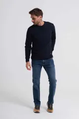 Pantalón de jean azul de corte slim, con diseño clásico de cinco bolsillos, trabillas para cinturón y cierre frontal con botón y cremallera.