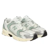 Championes New Balance modelo 530, con diseño retro de running. Presentan una base de malla blanca con superposiciones de cuero sintético en color blanco, detalles en verde menta y acentos plateados. Cuentan con entresuela amortiguada y suela de goma negra.