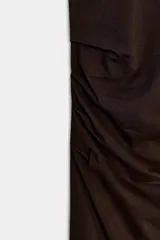 Vestido largo color marrón oscuro, con cuello redondo, manga corta y detalle de drapeado fruncido en el lateral izquierdo, terminando en línea evasé.