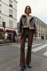 Pantalón de tiro alto color marrón oscuro, con corte flare (campana) y nervio marcado en el frente de ambas piernas. Presenta bolsillos delanteros y bolsillos de plastrón en la espalda.