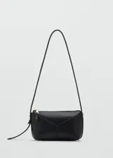 Cartera bandolera de poliuretano color negro, con diseño estructurado, costuras decorativas en V en el frente y cierre superior metálico dorado.