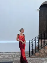 Vestido largo de microtul con estampado abstracto en tonos rojos y naranjas, con escote drapeado y tirantes finos.