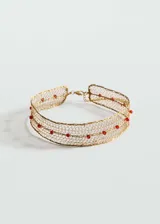 Gargantilla estilo choker de malla metálica dorada con pequeños abalorios de cristal rojo incrustados, cuenta con cierre de mosquetón y cadena de ajuste.
