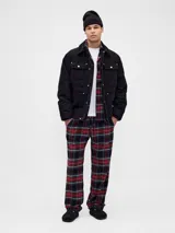 Set de pijama para hombre compuesto por una camisa de manga larga con cuello clásico y cierre frontal de botones, y un pantalón de corte recto con cintura elástica. Ambas prendas presentan un diseño de estampado a cuadros en tonos rojo, verde, azul y negro.