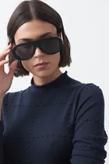 Polera de tejido de punto color celeste, con cuello alto y textura de pequeños puntos en relieve formando una cuadrícula en el frente y las mangas. De corte ajustado y manga larga.