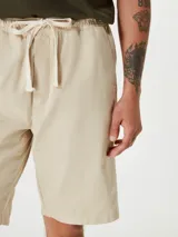 Bermuda de corte recto en color negro, confeccionada en tejido de algodón, con cierre frontal y bolsillos laterales.