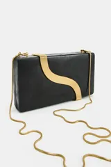 Bolso tipo clutch negro de formato rectangular con diseño rígido, adornado con un detalle metálico dorado de líneas onduladas en el frente. Cuenta con un cierre imantado y una correa de cadena metálica fina y dorada para llevar al hombro o cruzada.