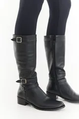 Bota de caña alta de cuero liso negro, con diseño clásico, detalles de hebillas metálicas, cierre lateral y taco bajo.