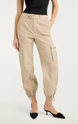 Pantalón cargo color beige de tiro alto, con bolsillos laterales con solapa y ajuste con lazos en los tobillos.