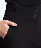 Bermuda roja de poliéster con cintura elástica, bolsillos laterales y cierre con cremallera y botones.