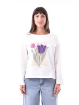 Remera blanca de manga larga con cuello redondo y un estampado central de tulipanes en tonos rosado y morado, sobre un fondo rectangular beige claro. Debajo del estampado se lee el texto "NEW YORK".