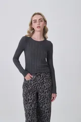 Remera de manga larga confeccionada en viscosa, con diseño entallado y cuello redondo a la base. Presenta una textura acanalada y terminaciones con ondas en los puños y el ruedo.