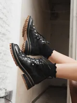 Borcego de cuero negro con cordones y suela track color caramelo.