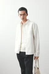 Sobrecamisa color crema de sarga de algodón, corte regular, con cuello inglés, tapeta clásica, bolsillo de parche en el pecho, mangas largas con puños abotonados y bajo recto.
