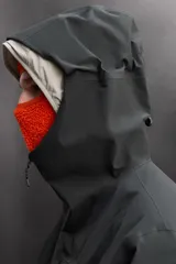Cazadora deportiva de esquí con diseño bicolor en tonos negro y verde oliva. Presenta capucha amplia con visera, cierre frontal con cremallera termosellada, bolsillos frontales y en manga con cierres impermeables, y aberturas de ventilación en las axilas. Incluye faldón interior antinieve, puños ajustables y tecnología de rescate RECCO.