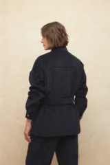 Sobrecamisa de pana color beige, con cuello camisero, cierre frontal con botones metálicos, mangas largas con puños abotonados y lazo ajustable en la cintura.