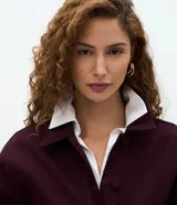 Campera bomber de sarga acanalada en color bordó, con cuello camisero, cierre frontal con botones forrados y puños con ajuste elástico.