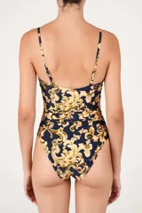 Malla enteriza de color azul marino con estampado barroco en tonos beige y dorado. Presenta un escote recto con tirantes finos, aberturas frontales unidas por argollas metálicas y laterales fruncidos.