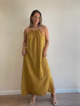 Vestido largo de lino color negro oscuro, con escote fruncido y tirantes finos ajustables. Presenta aberturas laterales en el ruedo.