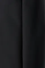 Pantalón negro de corte bootcut, con tiro alto, trabillas para cinturón y cierre frontal con botón y cremallera. Cuenta con pliegues marcados al frente y bolsillos simulados con solapa en la parte delantera.
