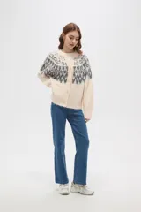 Cardigan de tejido jacquard con diseño geométrico en la parte superior, cuello redondo y cierre frontal con botones. Presenta un corte holgado y mangas largas con puños acanalados.