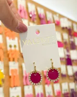 Aros colgantes con aro de acero dorado y dije circular fucsia con borde de strass. Marca Valente accesorios.