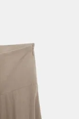 Falda midi color beige con bajo asimétrico y cierre lateral con cremallera oculta.