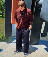 Remera color arena con cuello redondo y estampado frontal con letras "MTPE" en marrón.