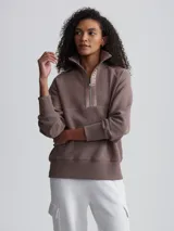 Buzo color marrón topo de tejido acanalado con cierre de cremallera metálica y cuello alto.