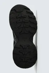 Zapatilla deportiva tipo running con diseño técnico, confeccionada en una combinación de malla y piezas sintéticas. Presenta cordonera curvada y una suela robusta con volumen y diseño irregular.