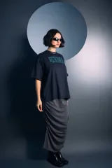 Falda midi de color gris, con diseño de frunces laterales que crean un efecto drapeado y una abertura lateral. Confeccionada en tejido de punto con textura.