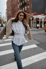 Camisa de popelín color celeste, con cuello solapa, manga larga y cintura entallada con pliegues. Presenta cierre frontal con botones ocultos por solapa.