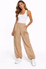 Pantalon cargo color camel con cintura elastizada, bolsillos laterales amplios con cordones ajustables y tobillos con cordón regulable.
