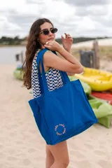 Bolso tipo tote bag azul con asas al hombro.