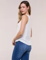 Musculosa blanca de tejido acanalado, con escote redondo adornado con tachas metálicas en el borde y breteles anchos.