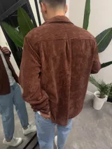 Sobrecamisa de pana color marrón chocolate, con cuello clásico, cierre frontal de botones y un bolsillo en el pecho.