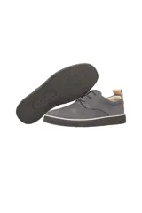 Zapato de vestir estilo derby, color gris oscuro (magnet), confeccionado en gamuza o nobuck. Presenta cordones finos y una suela de goma gruesa y texturizada de color negro con una fina línea blanca que la separa del cuerpo del zapato. Posee un tirador de cuero color camel en el talón.
