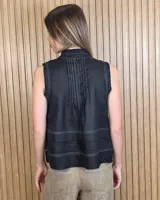 Musculosa marrón sin mangas, con cuello alto, escote en V y detalles de pespuntes blancos en contraste. Presenta pliegues y alforzas frontales.