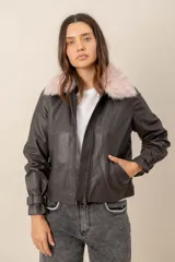 Campera de cuero color marrón oscuro con cuello desmontable de piel sintética rosada y cierre frontal de cremallera. Cuenta con bolsillos laterales y detalles de presillas en los puños.